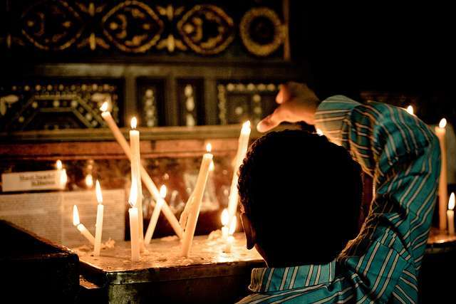 Coptic Christian boy lights a candle at a church in Cairo Credit Christopher Rose via Flickr CC BY NC 20 CNA EU REPORT HIGHLIGHTS RELIGIOUS FREEDOM THREATS ACROSS THE GLOBE
